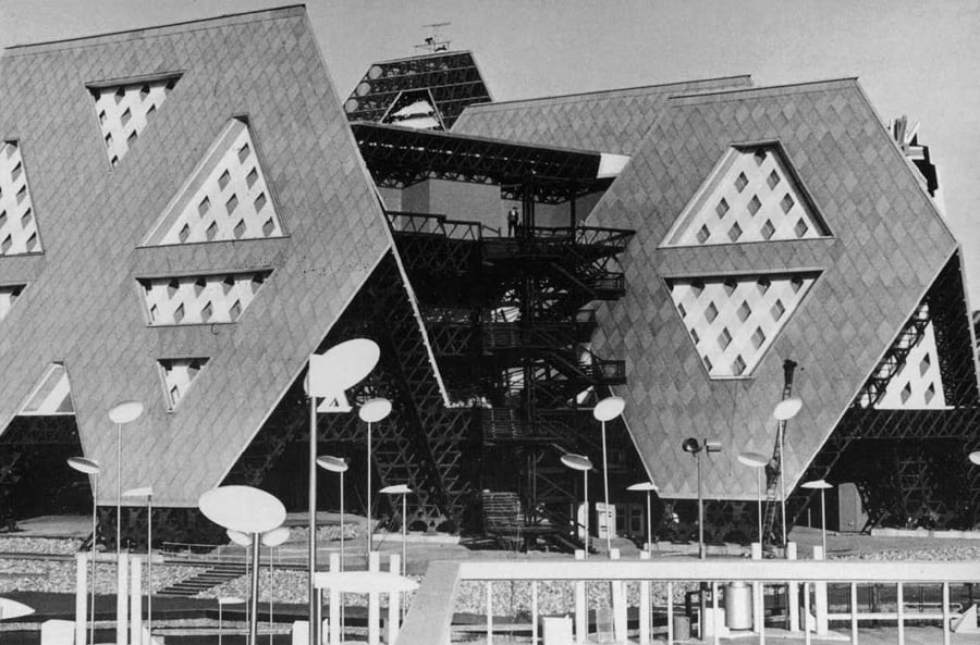 A black-and-white photograph of a building with a geometric roof 