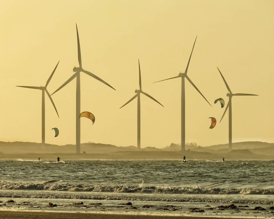 five wind turbines against a dusty sepia-toned beach, for Earth Day