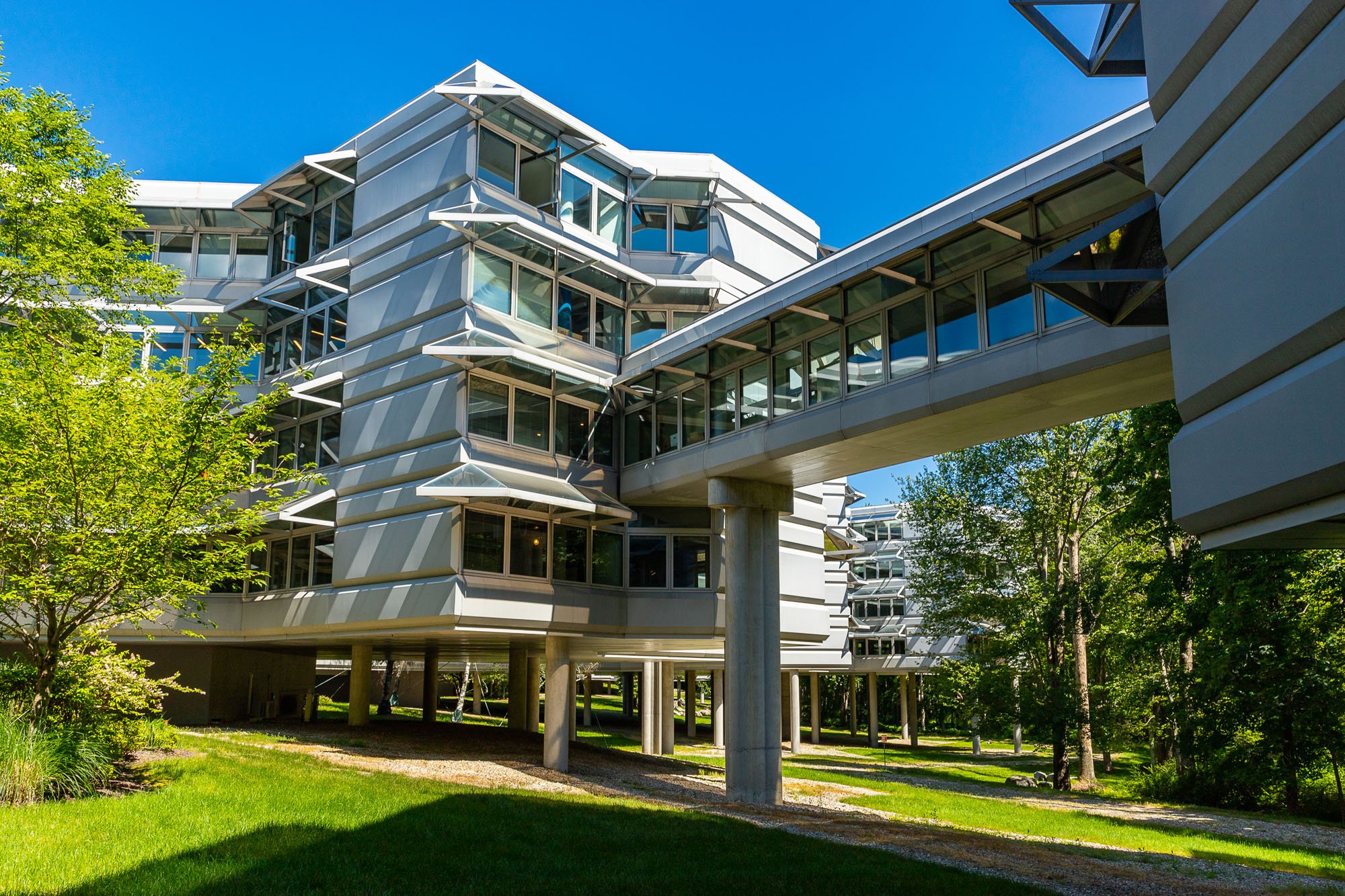 A photograph shows an elevated walkway connecting two pods, surrounded by greenery