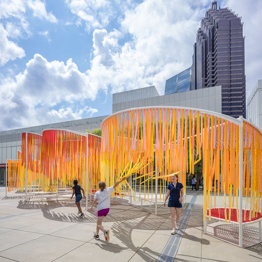 Kids interacting with orange ribbons suspended from Byrony Robert's Outside the Lines installation at the High Museum of Art in Atlanta, Georgia. 