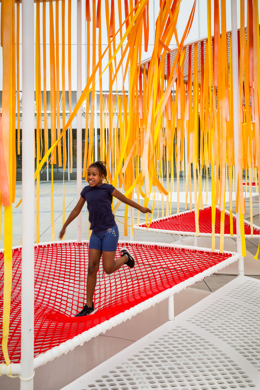 A young girl jumps on a mesh trampoline section of Byrony Robert's Outside the Lines installation at the High Museum in Atlanta, Georgia. 