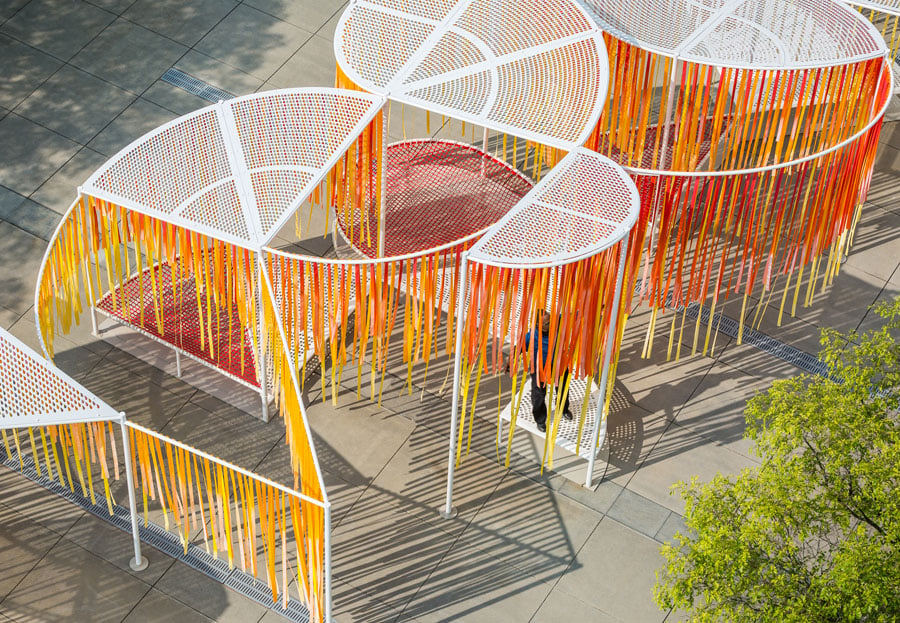 People interacting with an interactive orange and white installation in a concrete plaza outside of the High Museum of Art in Atlanta, Georgia. 