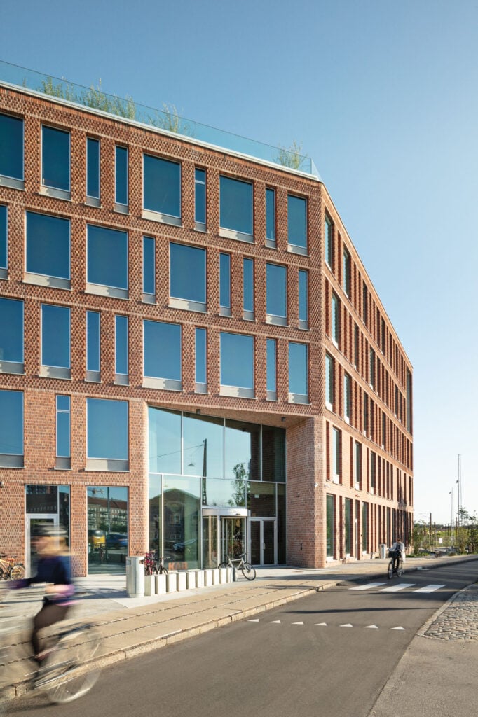 brick and glass facade with a bicycle path in foreground.