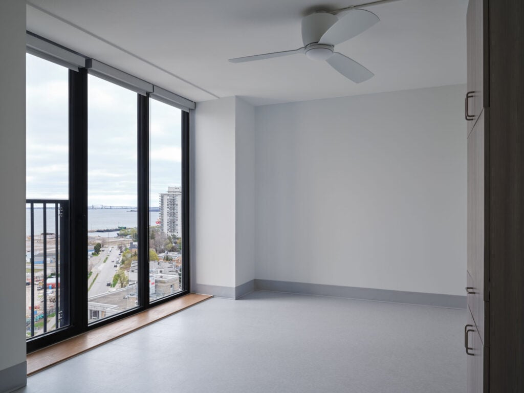 interior of apartment with fan and full heigh windows.