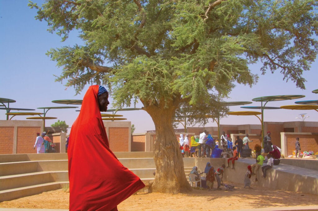 regional market rendering with people sitting under a tree and woman in red in foreground