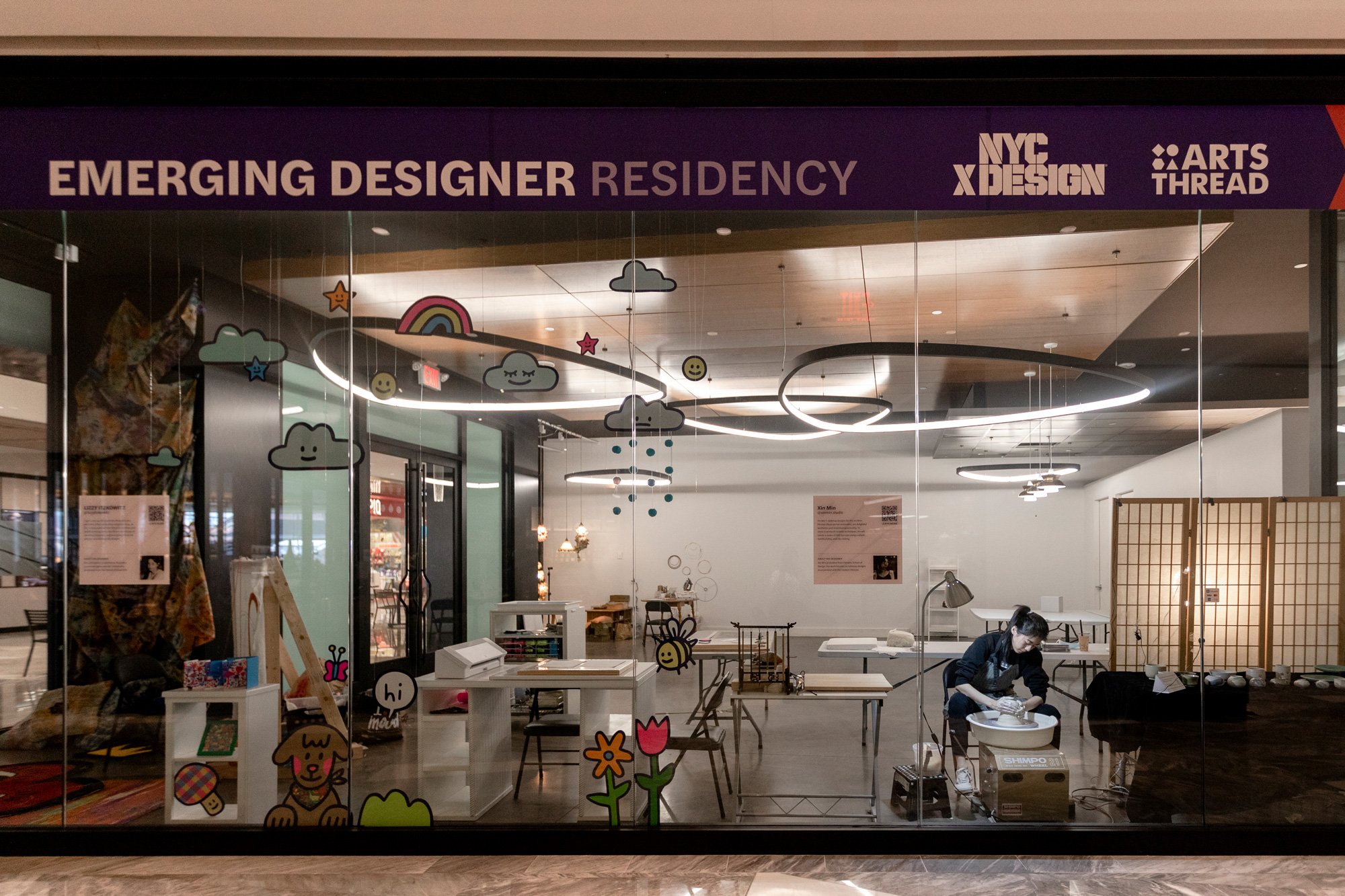 storefront with design objects and person working on pottery wheel