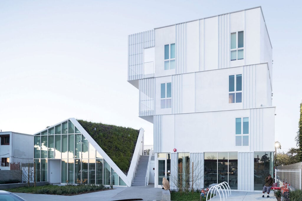 photograph of housing development white facade and green roof