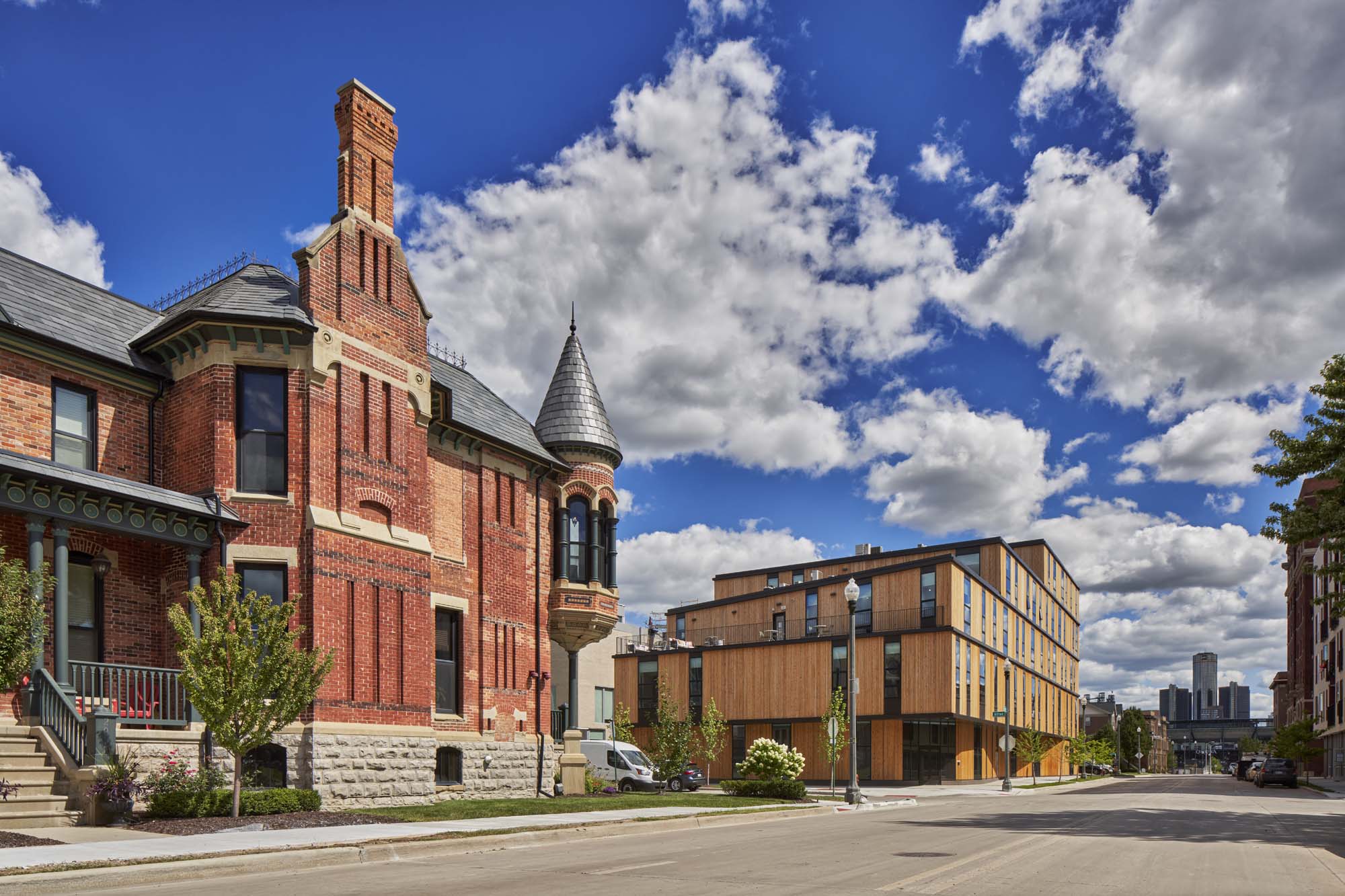 A red brick victorian building next to a modern wooden one