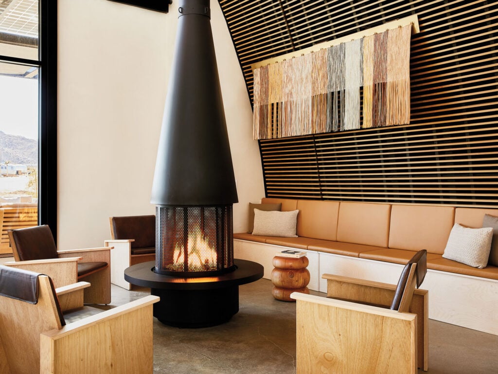 a black metal fireplace with wooden accents behind and chairs