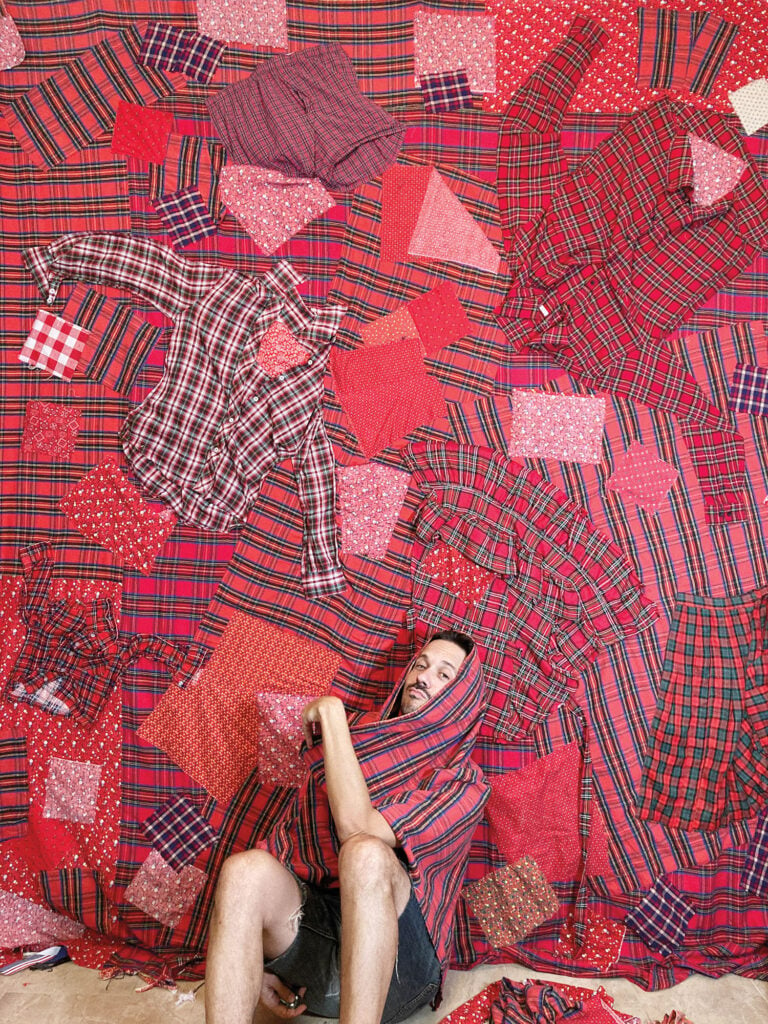 person wrapped in red cloth sitting in front of red quilts