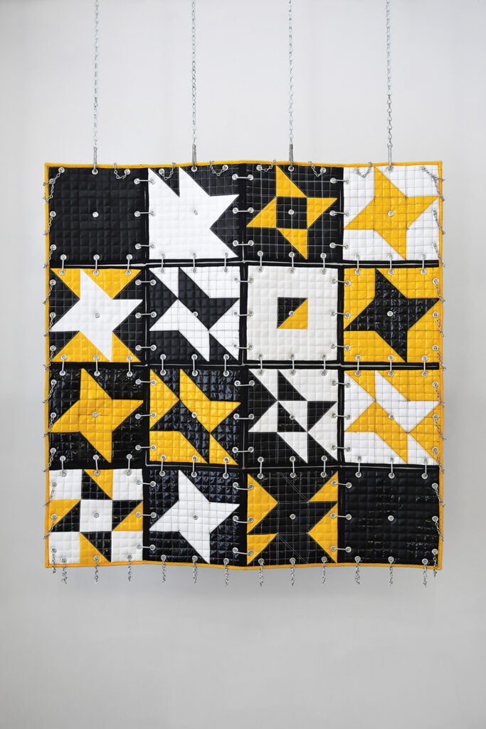 yellow, black, and white quilt hanging in a gallery