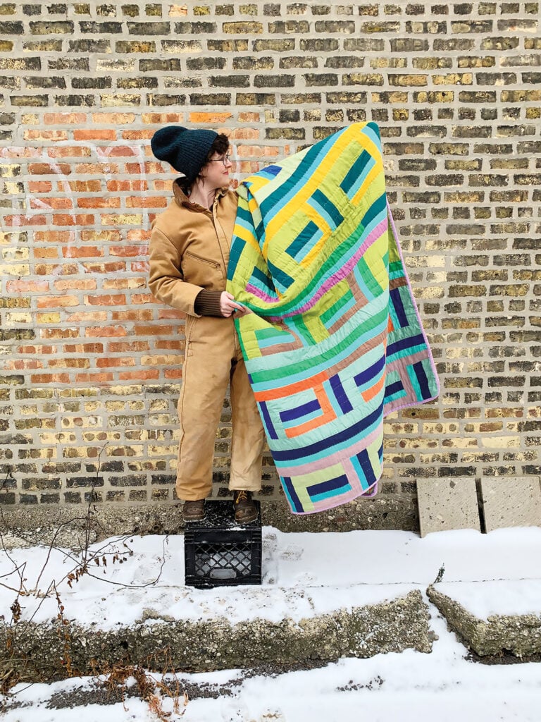 Person holding one of their quilts  with a yellow and green pattern