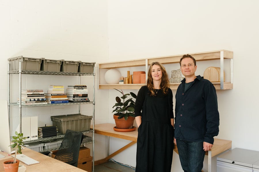 Two people in an office with wood desk and storage