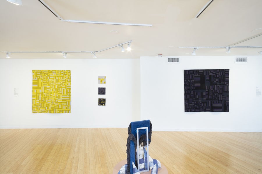 an image of the interior of an art gallery with five quilts on the walls 