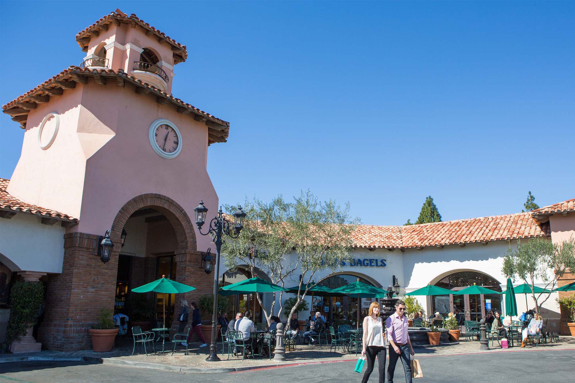 A clock tower in the village at Moorpark courtyard with shoppers walking