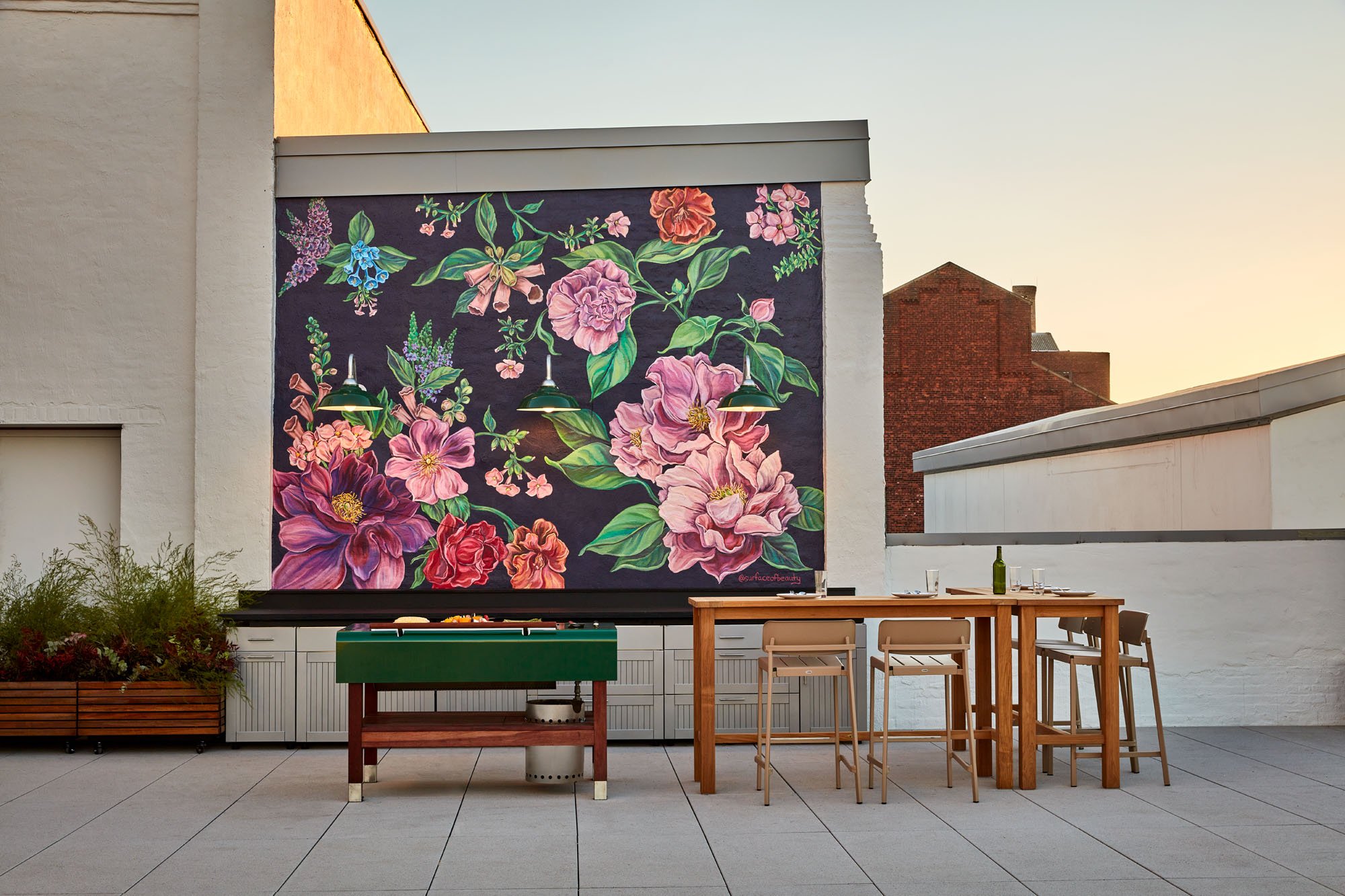 a photograph of a table set on a roof patio with a mural of flowers in the background 