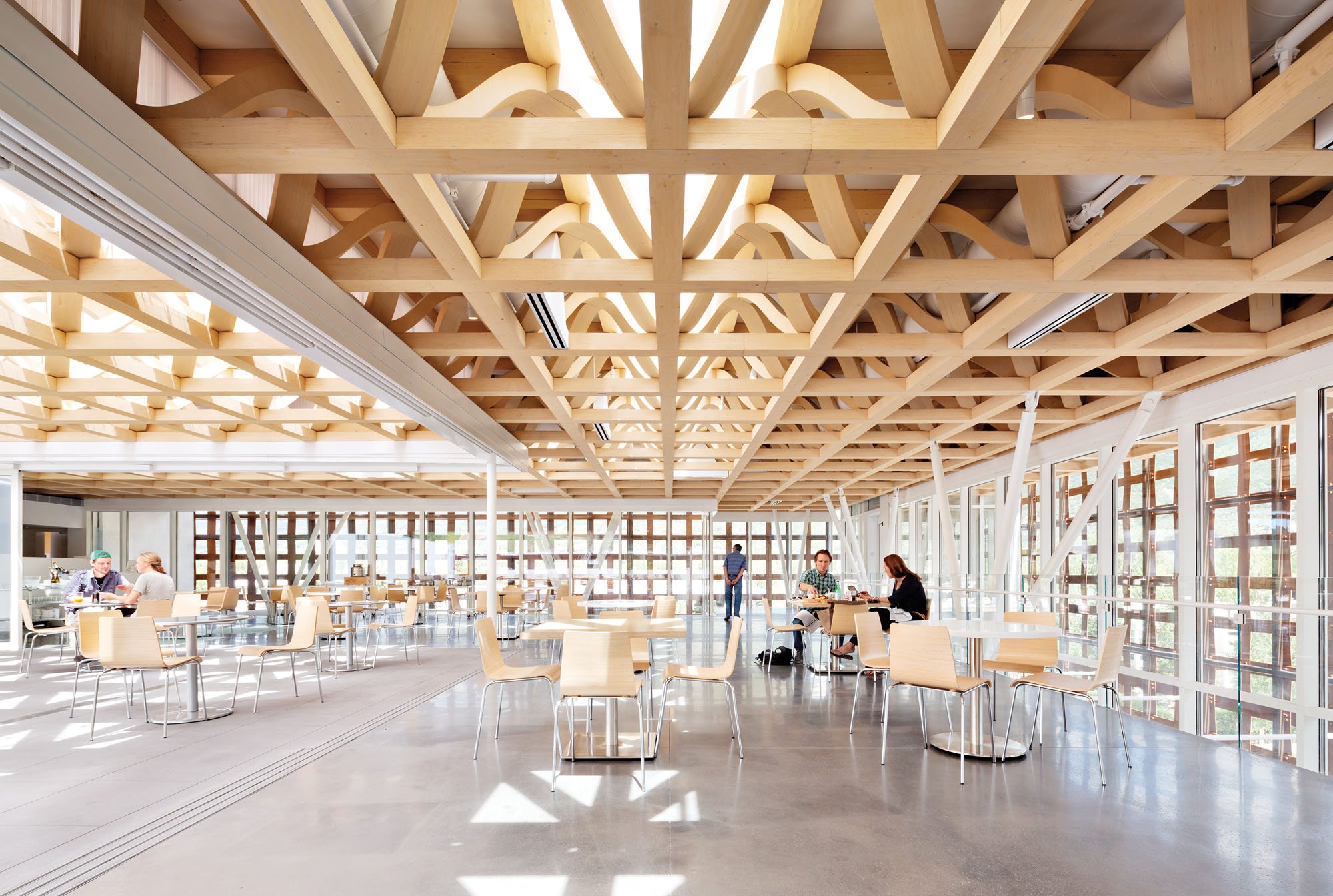 the interior of a cafeteria with a wooden lattice roof