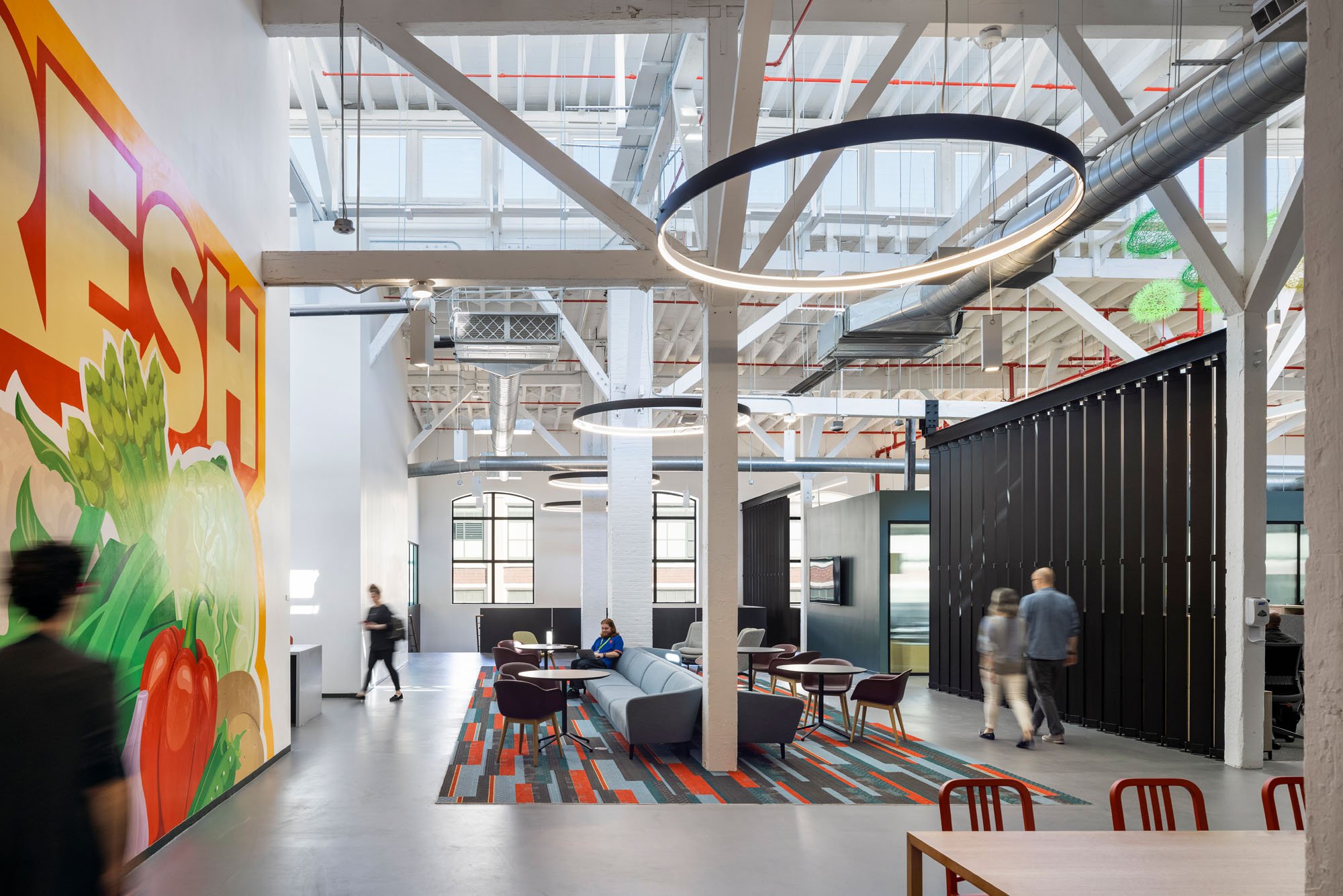 a photograph of an office on the second floor with a mural on one side, the ceiling is open to expose the building's wooden truss structure