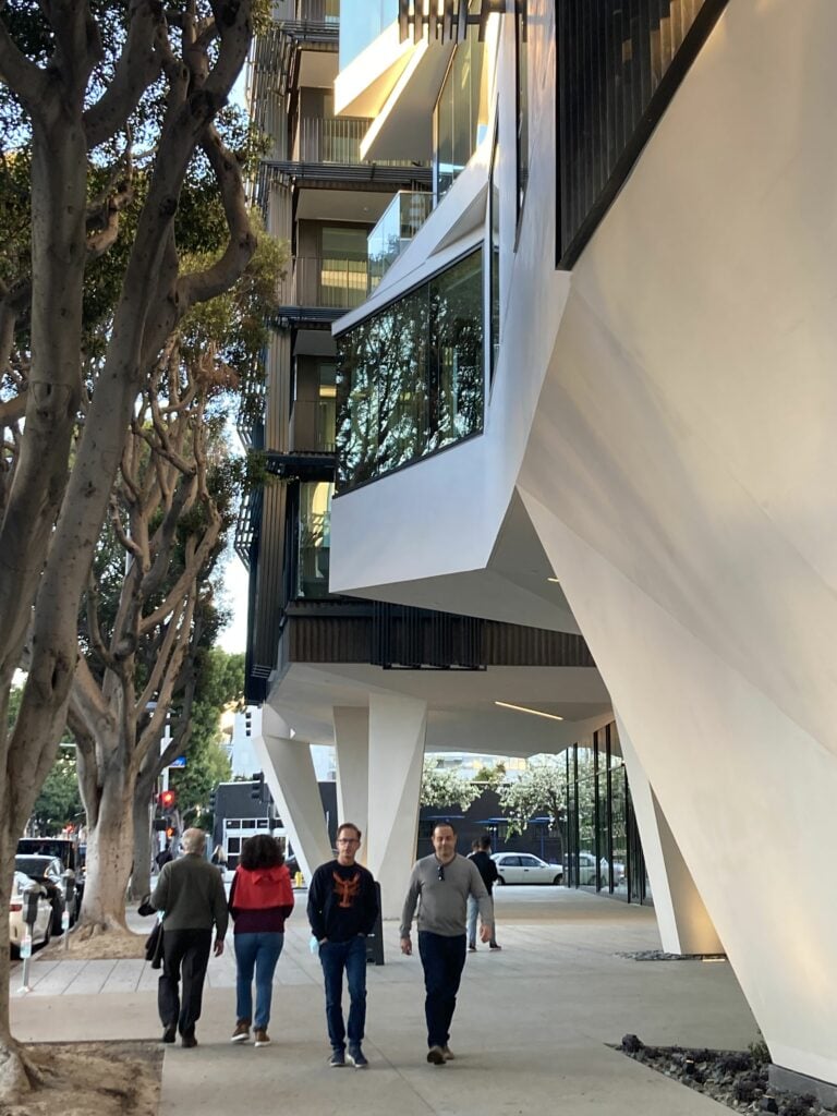 Una acera con gente caminando bajo columnas de concreto