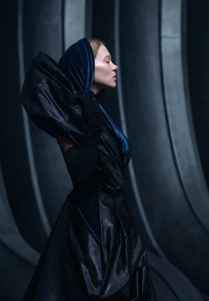 A still from Dune with a woman in a black hooded robe against a black background