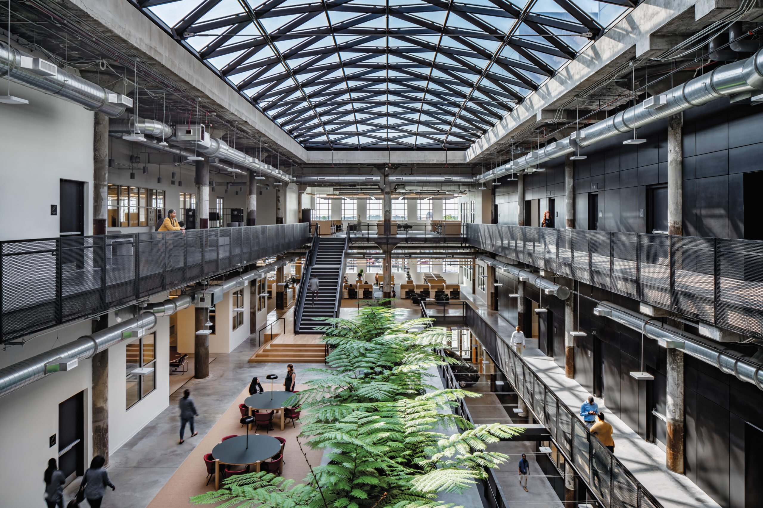 inside the building with passage walkways on either sides and stairs going up from the foyer and the ceiling covered in glass.