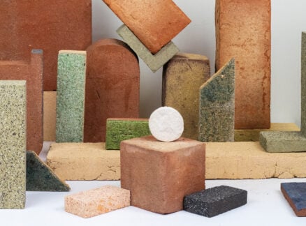 Multiple blocks with curved corners and edged corners in earthy colors made from waste materials and a white ball like structure.