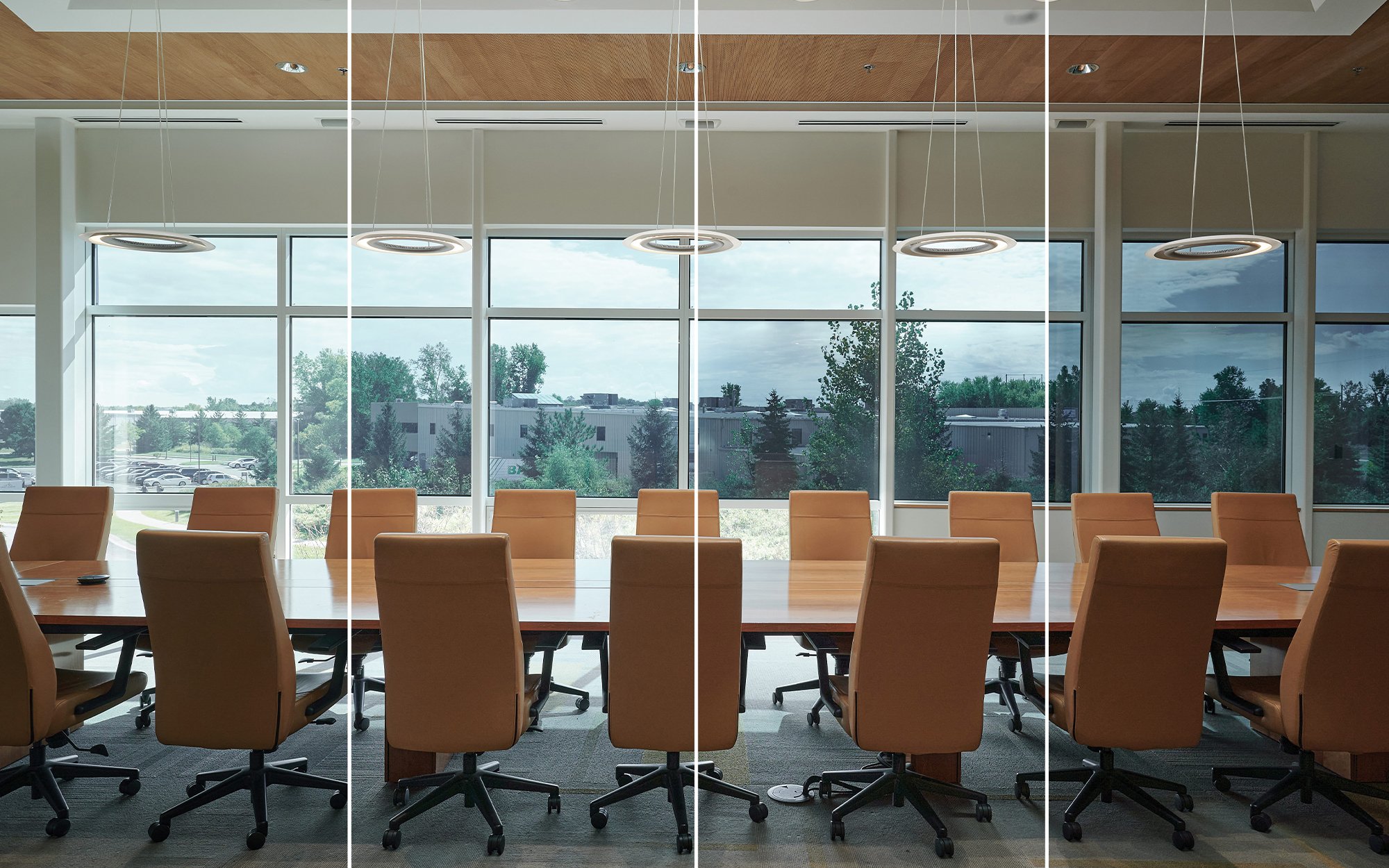 A conference room with large transparent glass and tan leather chairs.