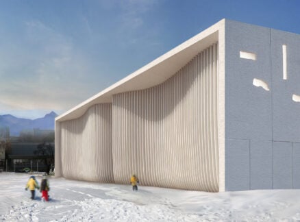A snowy exterior of a stark white building with curvy facade added to a clay white box like building structure.