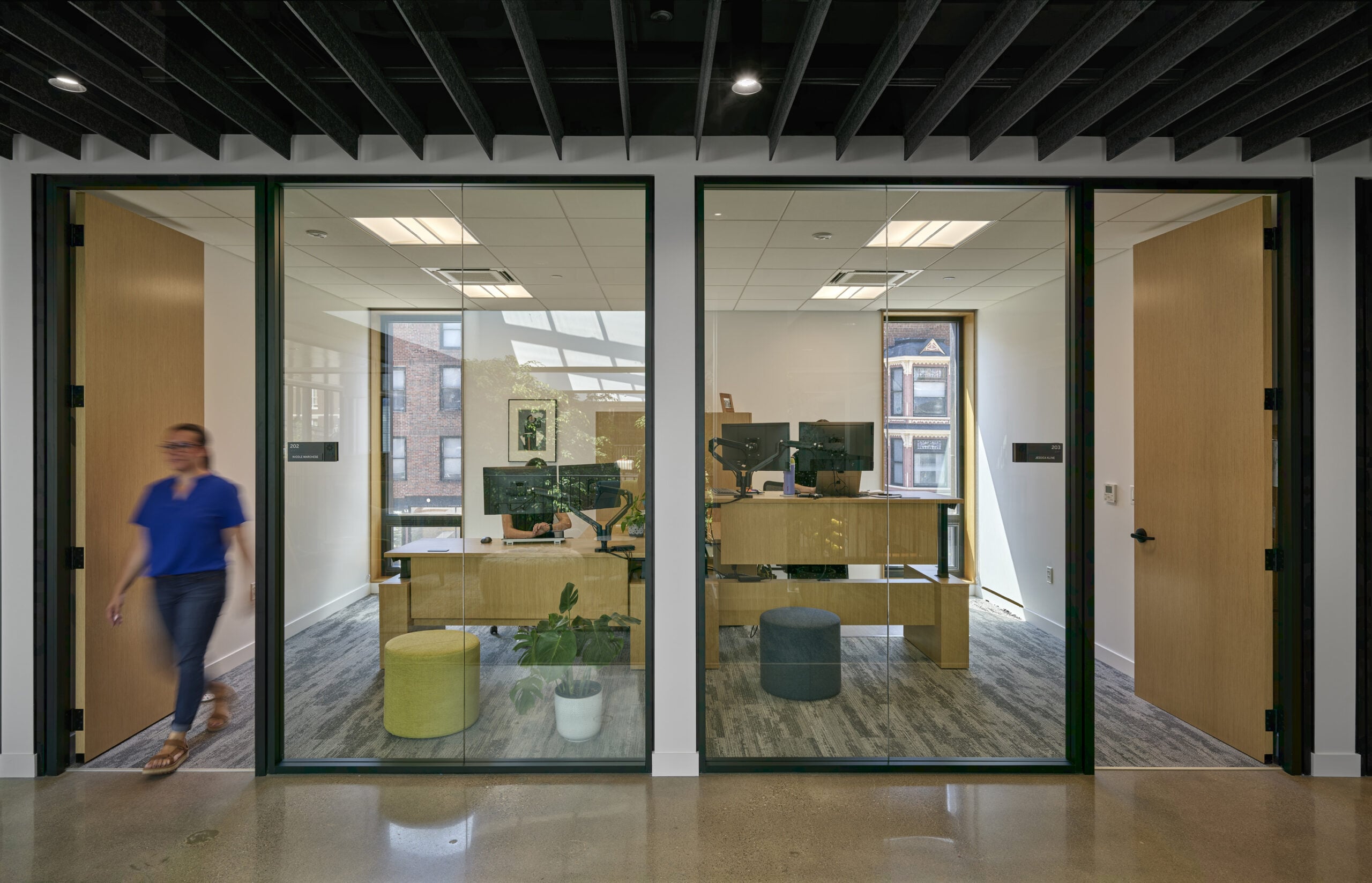 A person walking out of an office space with large clear glass all around.