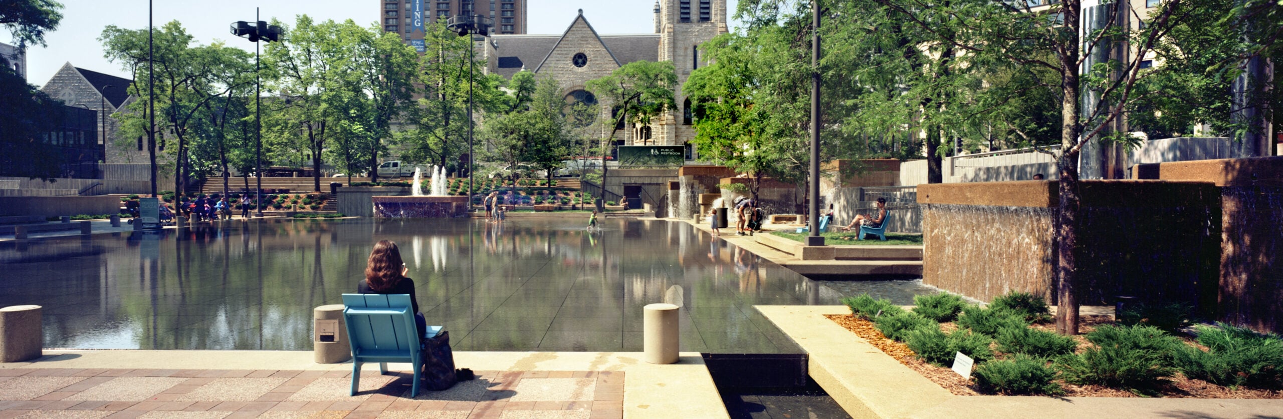 image of a concrete fountain and urban plaza in minneapolis with people lounging around the pool