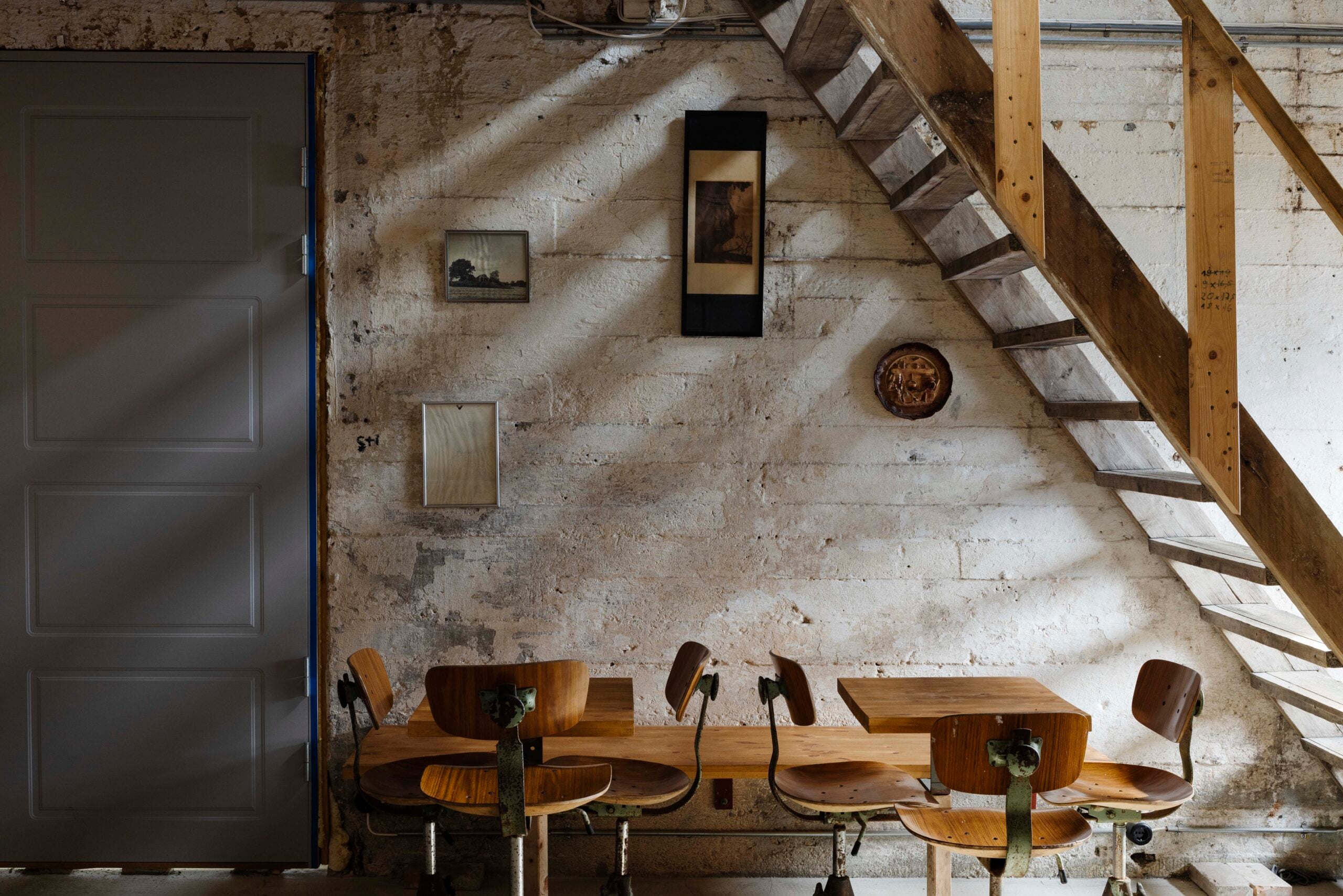 interior of a cafe with two tables and a set of stairs made of timber