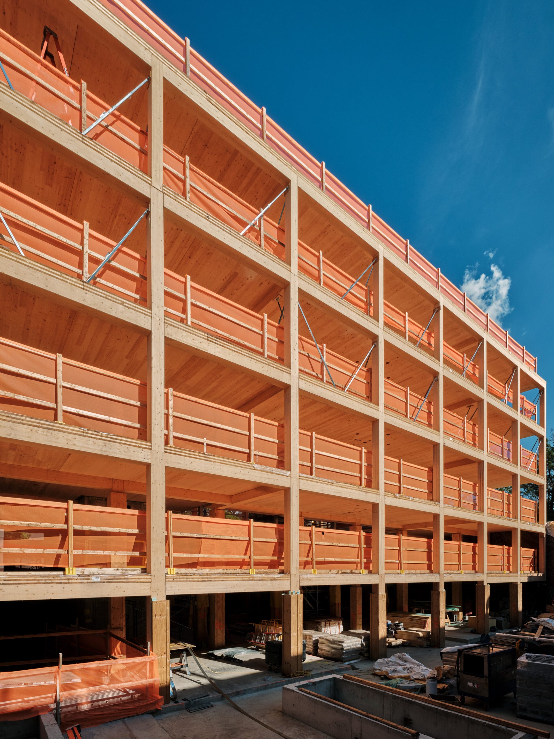 A construction photo displaying the building's exposed mass timber structural skeleton, with wooden beams and columns clearly visible before the exterior cladding was applied.
