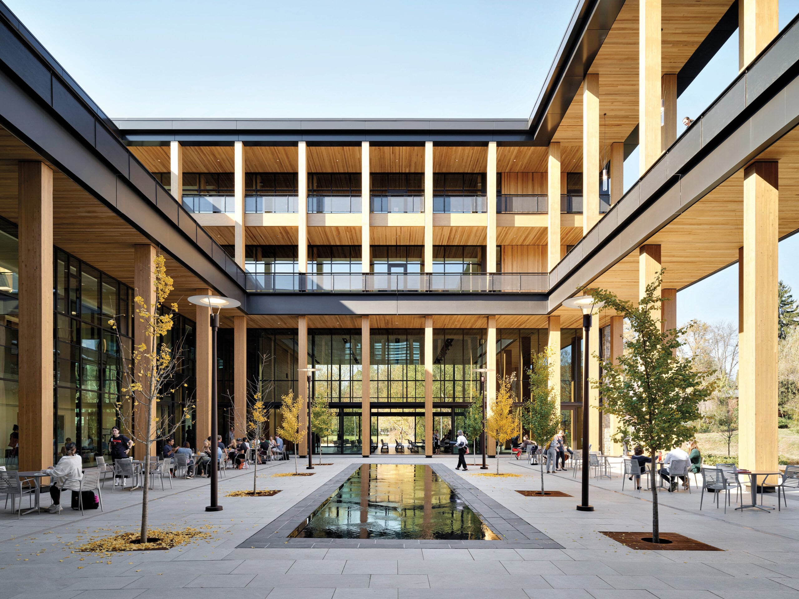 Central campus courtyard with mass timber beams, stone walls, outdoor seating and flexible learning spaces