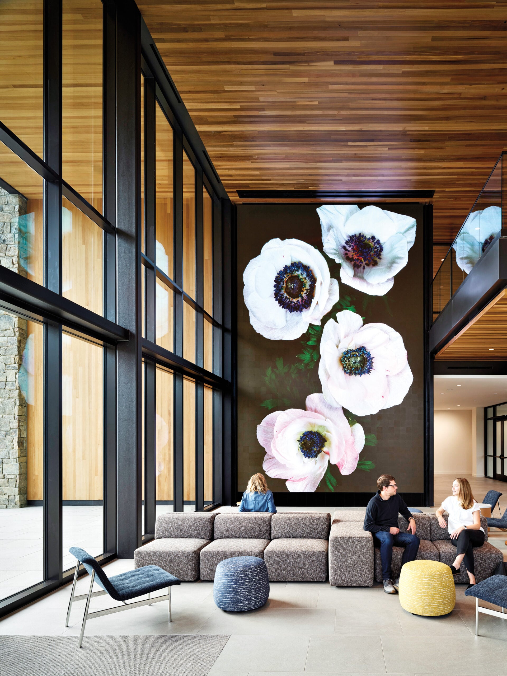 Campus building interior: floor to ceiling artwork of peonies cover one wall, with soft seating in front