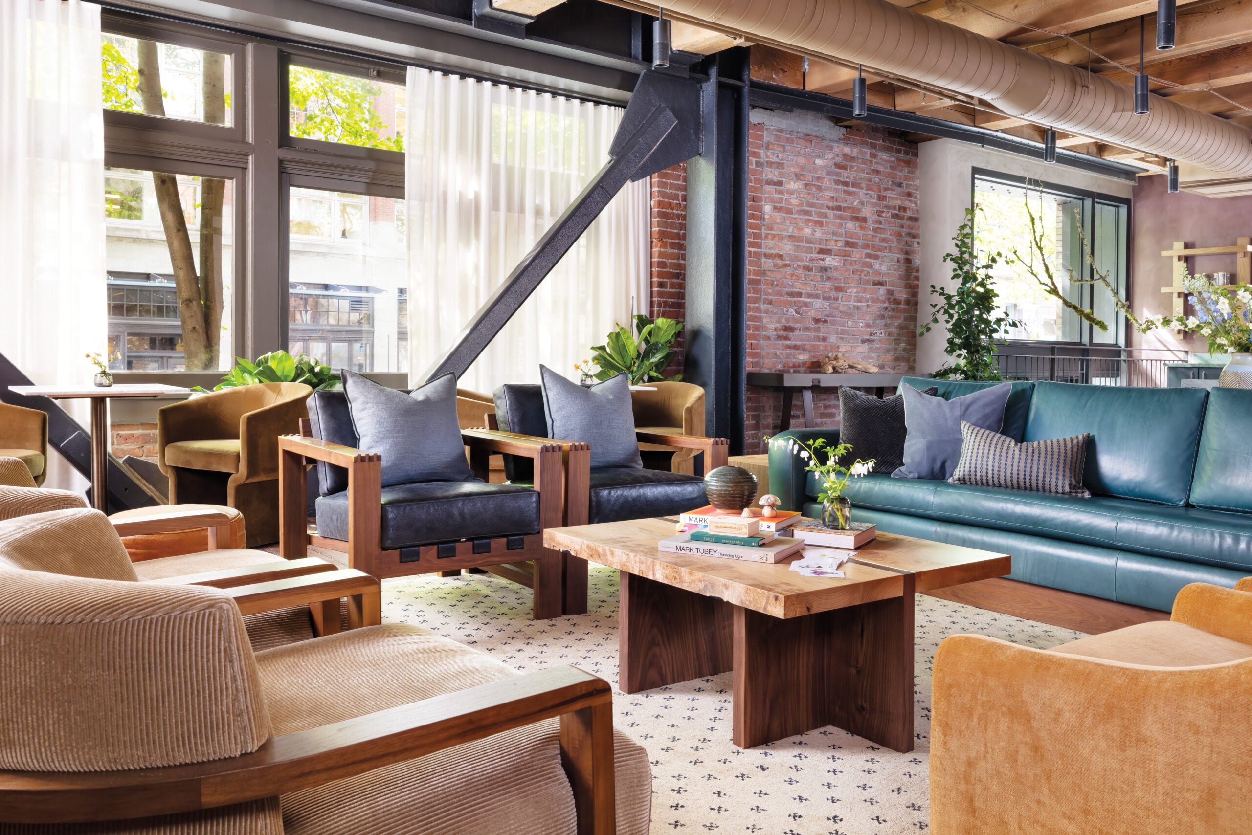 modern hotel interior seating area with wood coffee table, soft seating and exposed brick walls and metal structural supports