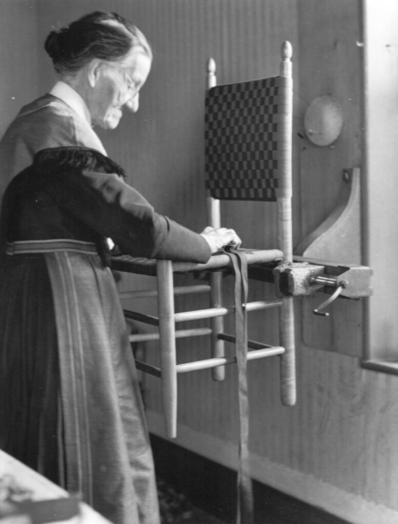 Black and white photograph of woman building a chair