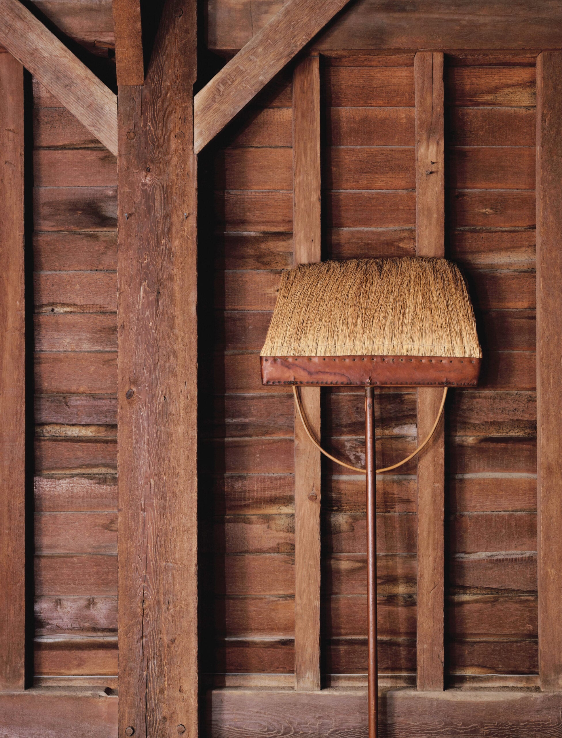 Flat broom leaning against wood, barn wall