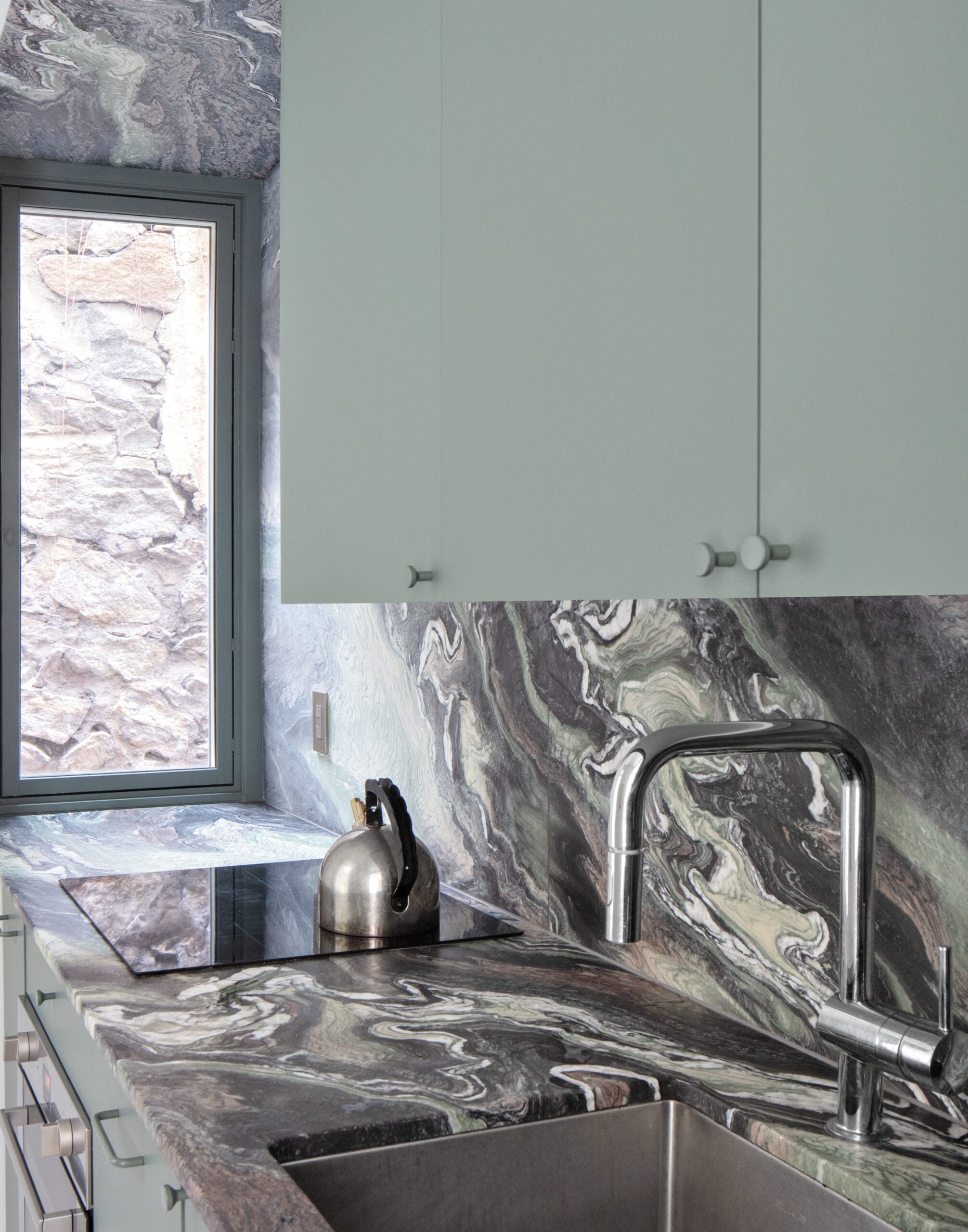 Interior kitchen with marbled countertop and light green cabinetry