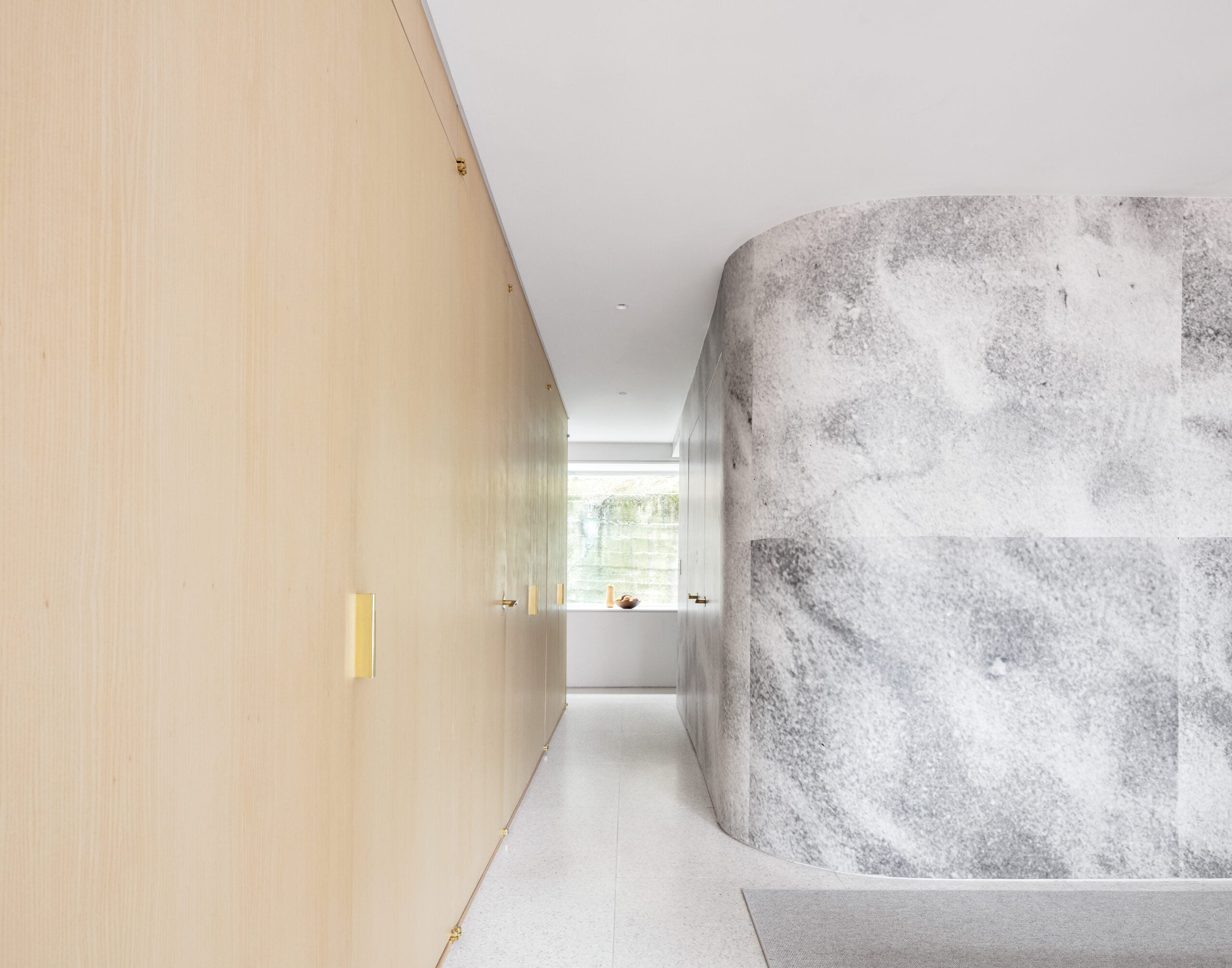 House interior with a wood cabinetry wall and curved stone wall forming a hallway
