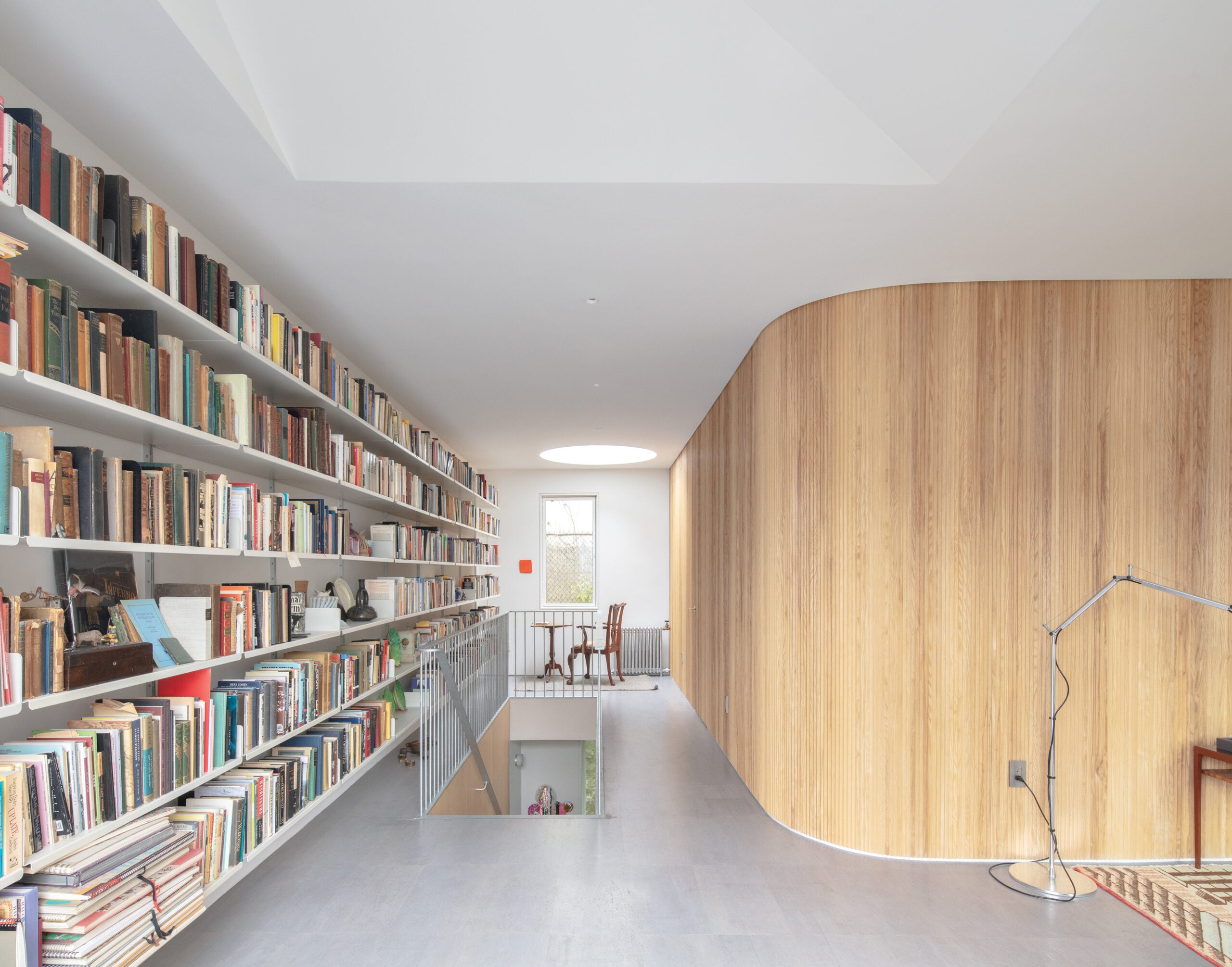 Interior home with curved wood wall and long wall-to-ceiling bookshelf