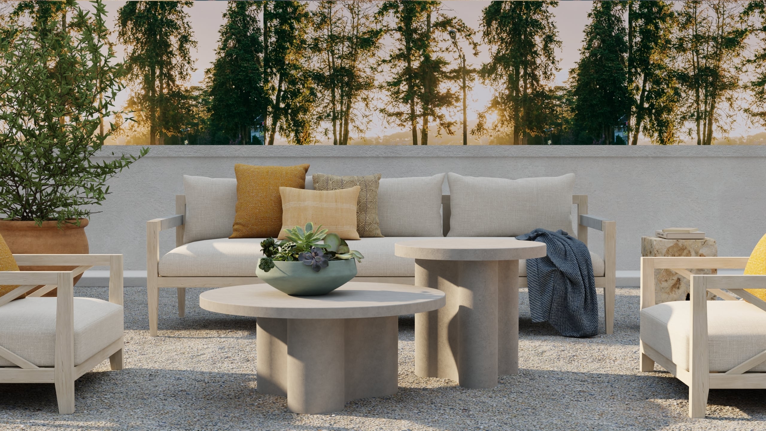 Outdoor patio seating area with beige cushioned chairs and sofa, two round stone tables, potted plants, and decorative textiles like throw pillows, set against a backdrop of trees at sunset.