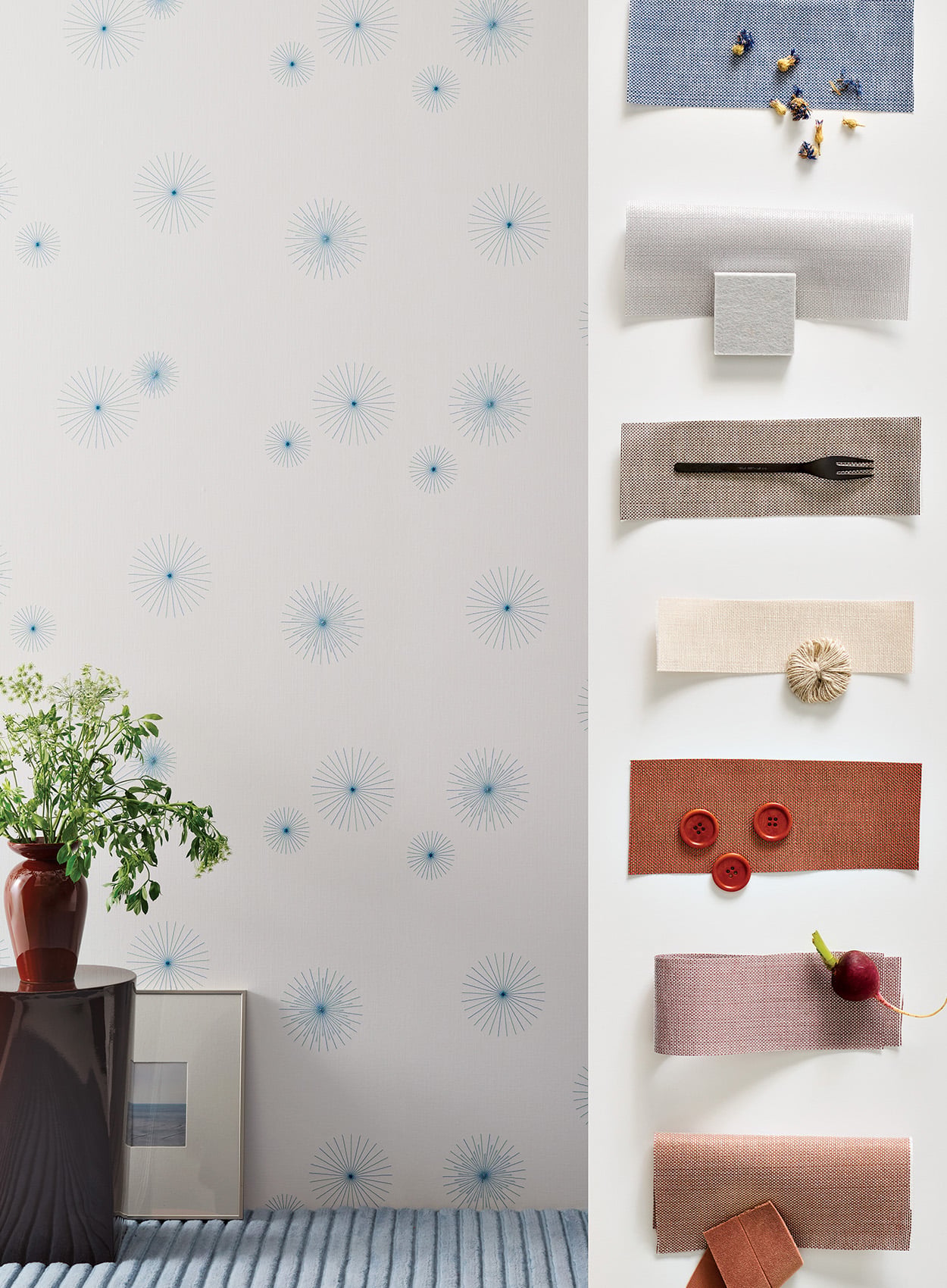 Fabric swatches in various colors and material textures are displayed vertically on a white background, next to a wall with a light blue starburst pattern and a plant in a red vase.