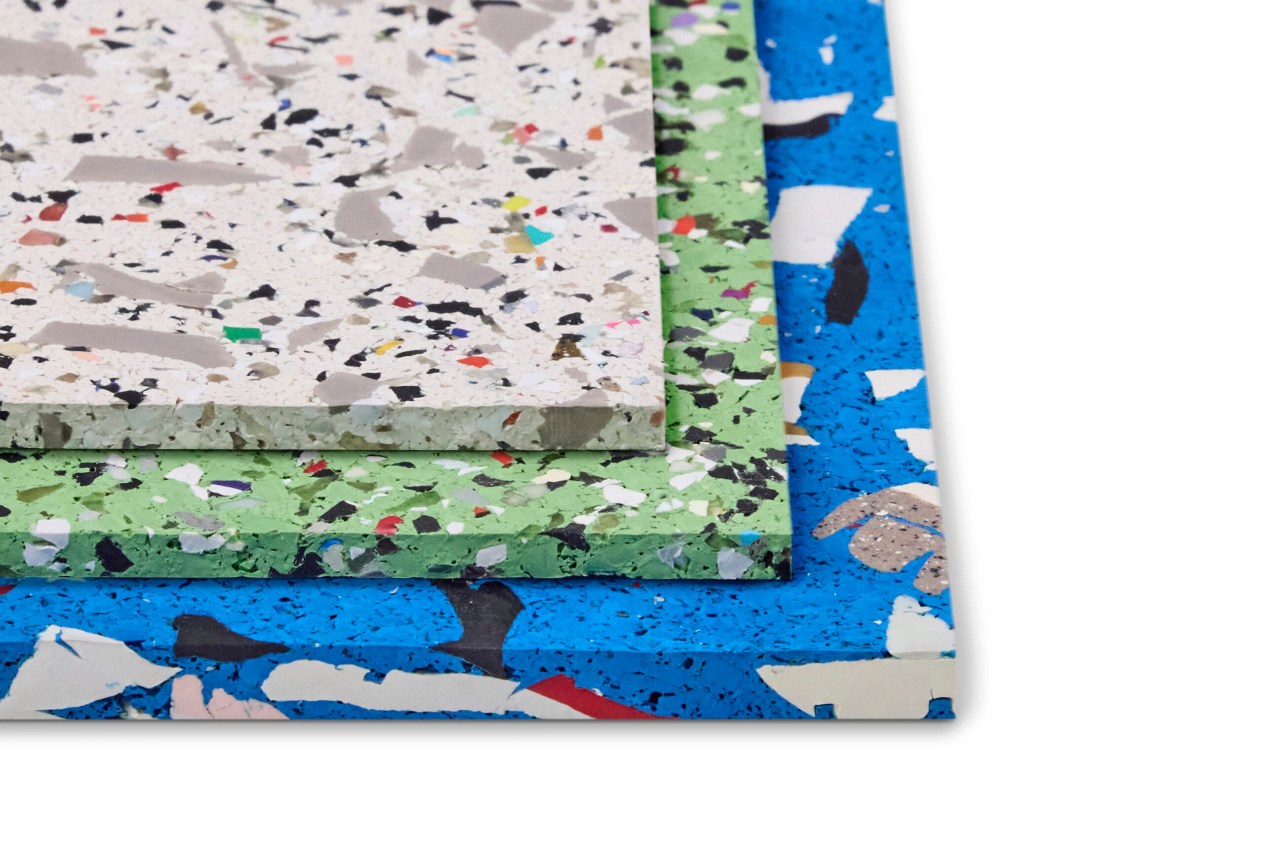 Three stacked rectangular terrazzo tiles in white, green, and blue with multicolored chips are displayed on a white background, highlighting the modern design seen at ICFF.