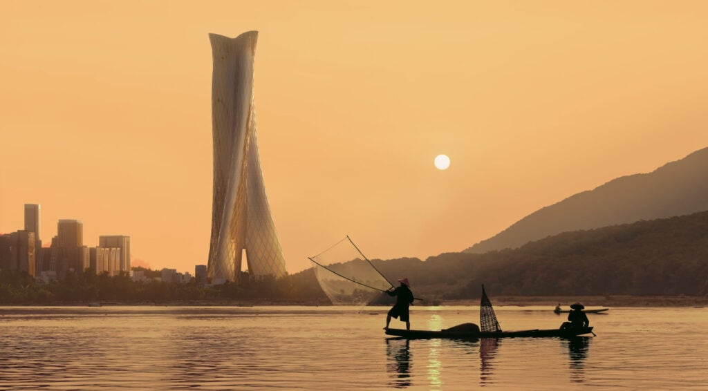 Two people in a small boat fish with a net on calm water at sunset, with a modern twisted skyscraper and city skyline in the background—an image capturing the spirit of progress celebrated by the 2026 Vision Awards.