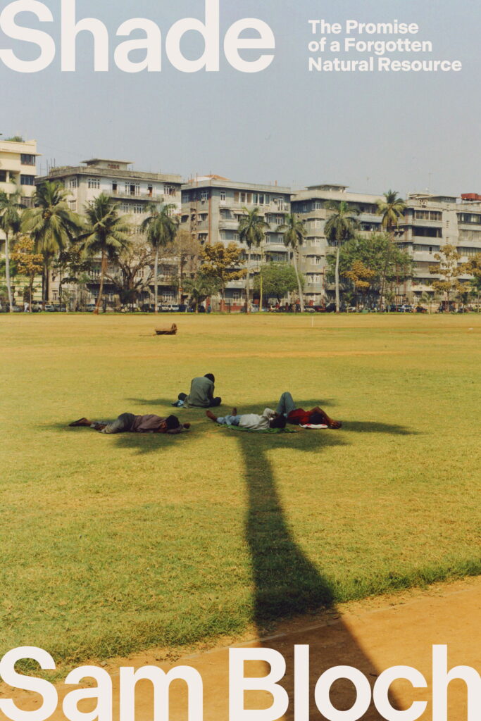Four people relax on the grass in the shade of a tall palm tree in a city park, with apartment buildings and more palms rising behind them. Text reads: "Shade" by Sam Bloch.