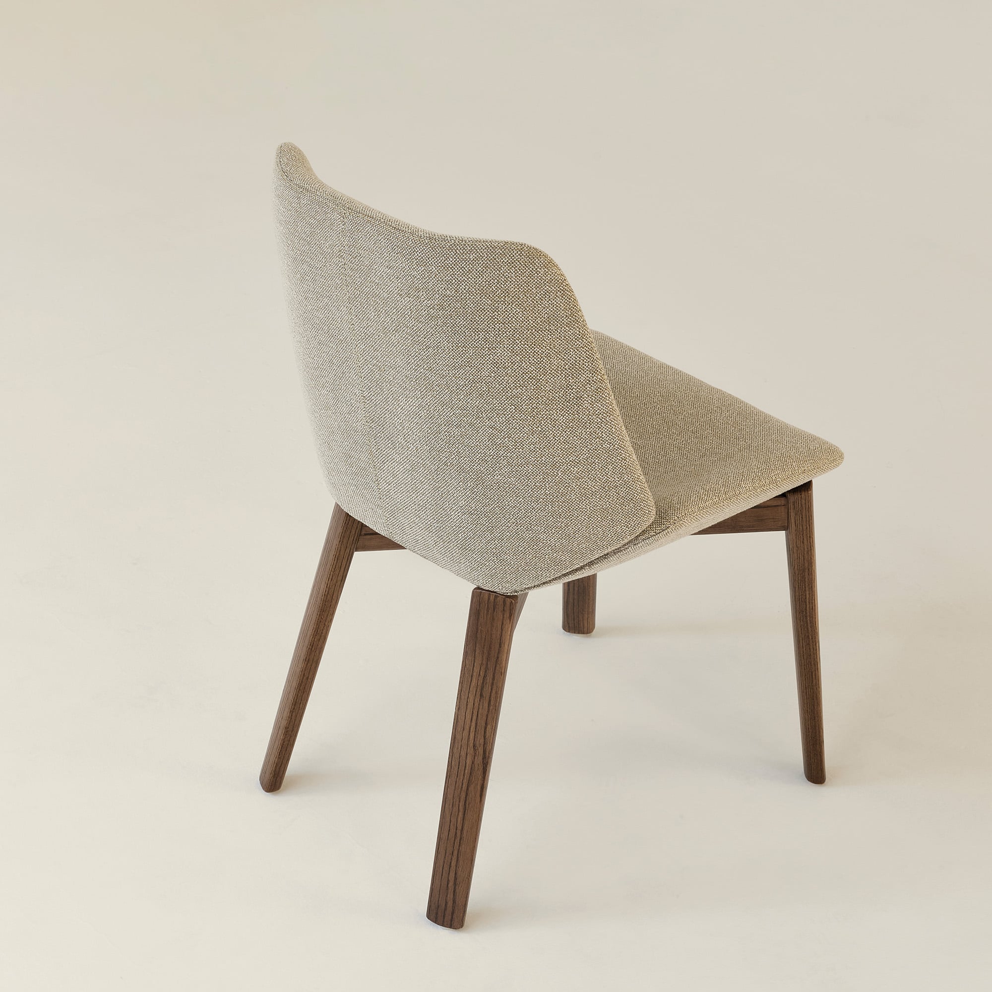 A modern chair with a beige upholstered seat and backrest, and four wooden legs, is shown on a plain light background.