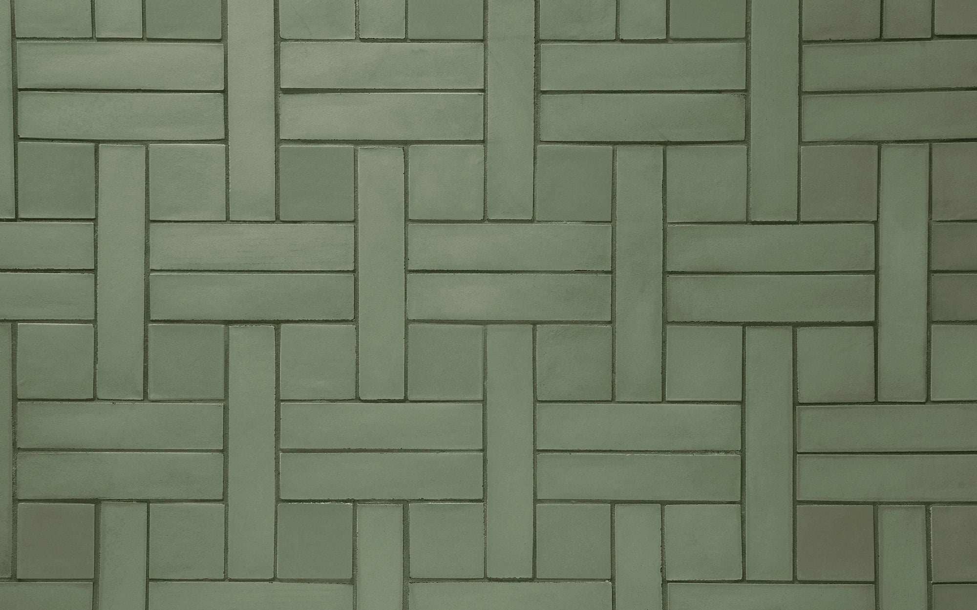 Green rectangular tiles arranged in a woven basketweave pattern, creating a repeating geometric design.