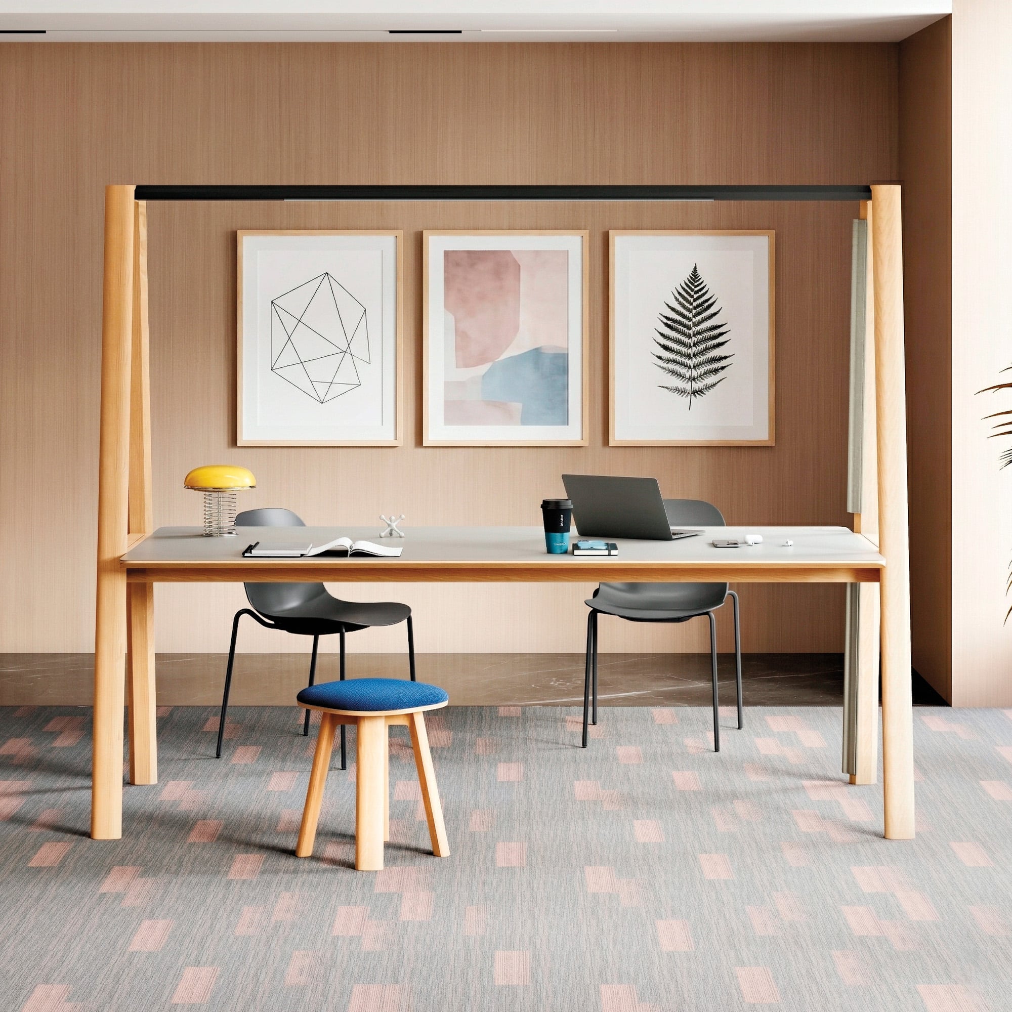 Office products: A modern office workspace with a large desk, two chairs, a laptop, books, a yellow lamp, and a small blue stool, set against a wall with three framed abstract art prints.