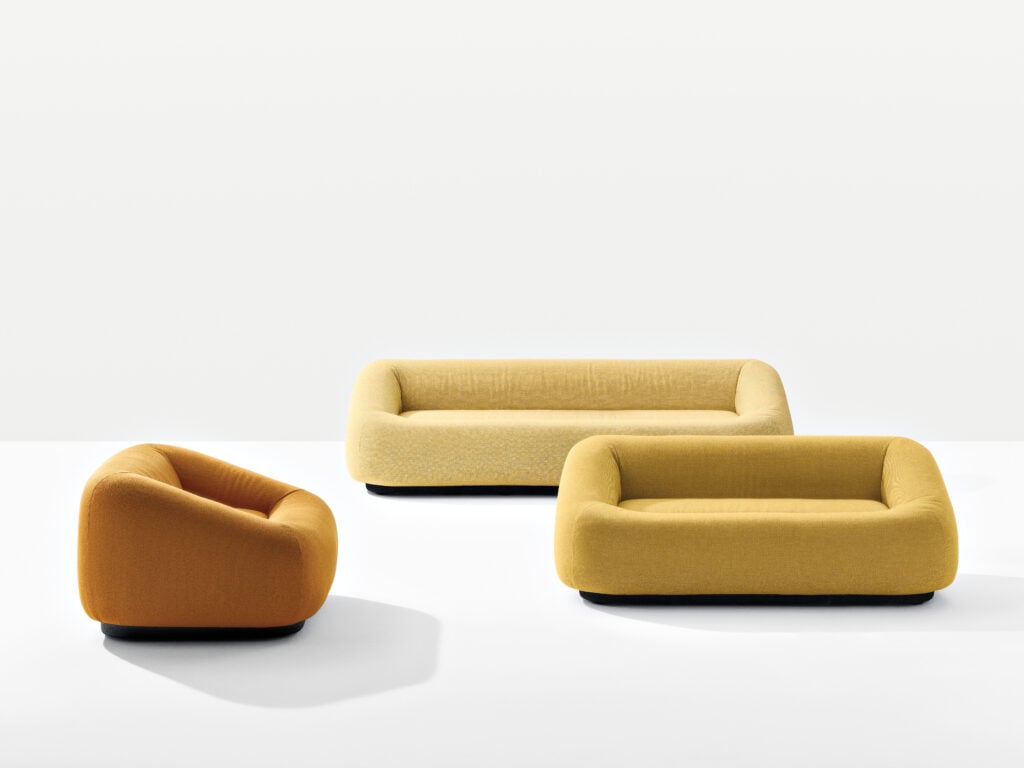 Three modern, low-profile upholstered seats in yellow and orange—part of the METROPOLISLikes collection—are arranged on a white background, including one armchair and two sofas.