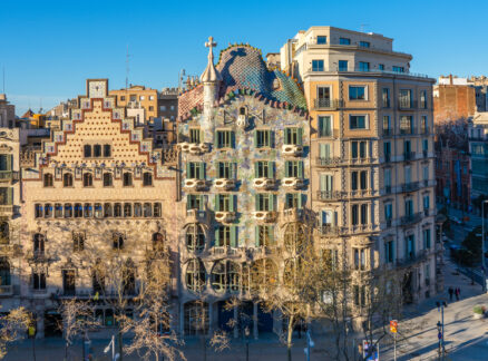 Casa Batlló and neighboring buildings in Barcelona, Spain, with ornate facades and a clear blue sky in the background.